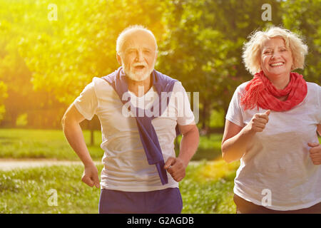 Two active happy seniors running in nature in summer Stock Photo