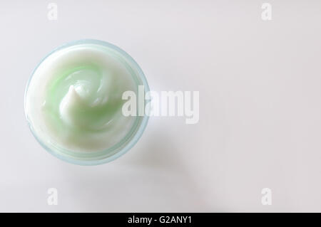 Glass open jar with facial or body cream on white table. Top view. White isolated. Stock Photo