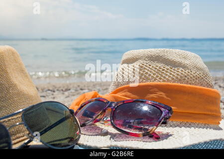 Two straw hats and sunglasses on the beach on a sunny day Stock Photo