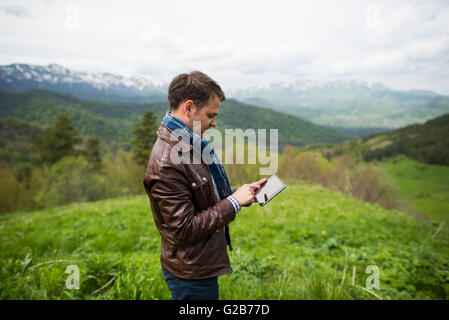 young man touching the tablet pc on the top of mountain Stock Photo
