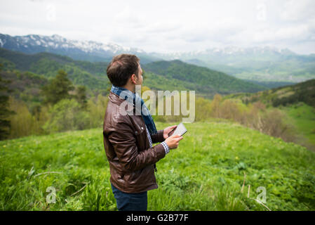 Man holding digital tablet on the mountain top Stock Photo