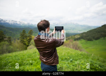 Adult european man taking selfie on tablet in mountains Stock Photo