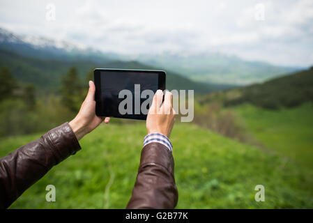 Young man taking tablet selfie on mountain Stock Photo