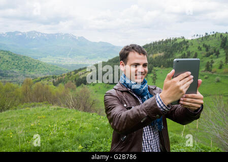 Young man holding digital tablet in front of him in nature Stock Photo