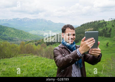Amazing man taking selfie with digital tablet in the mountains Stock Photo