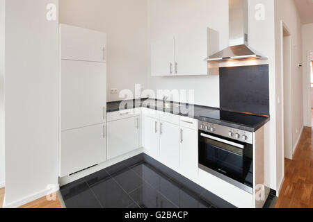 Conversion of Dach or Loft Space in Reichenberger Strasse, Kreuzberg. Modern sleek kitchen with white cabinets and black countertops. Tiled flooring. Stock Photo