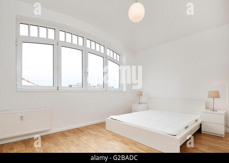 Conversion of Dach or Loft Space in Reichenberger Strasse, Kreuzberg. View of a modern bedroom with large wide windows. Contemporary furniture and minimal decoration. White walls and wood floors. Stock Photo