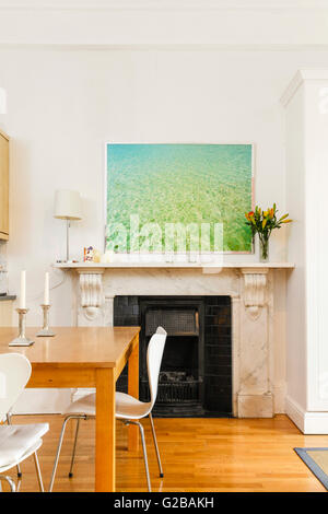 Pembridge Square, Notting Hill. View of a modern painting above a fireplace. Partial view of a wood dining table with white chairs. Wood floors. Stock Photo