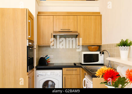 Pembridge Square, Notting Hill. Small kitchen with clean modern wood cabinets and counters. Partial view of a vase with flowers Stock Photo