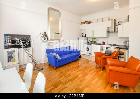 Pembridge Square, Notting Hill. Open plan living and dining room. Colourful contemporary couch and chairs. Wood floors and modern floor lamp. Stock Photo