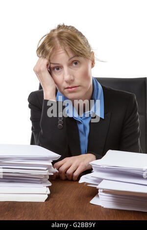 Over worked woman, rests her head on her hand, surrounded by big piles of paperwork, isolated on white Stock Photo