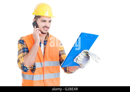 Young engineer wearing helmet with clipboard calling on cellphone as business conversation concept isolated on white Stock Photo