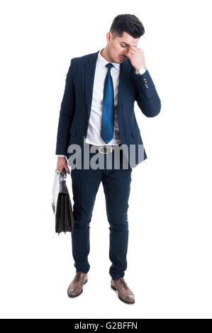 Tired corporate employee after work having a headache standing isolated on white background and holding briefcase Stock Photo