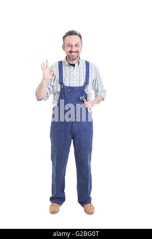 Trusthworthy mechanic showing ok gesture, holding mechanical tools and smiling isolated on white Stock Photo