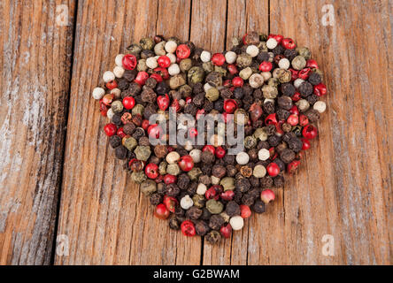 Color pepper mixed spices heart shaped  on old wood background Stock Photo