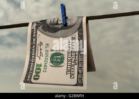 One hundred american dollar drying on string with cloudy  sky Stock Photo