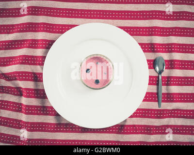 Overhead shot of a cup of yogurt on a white plate on a tea towel Stock Photo