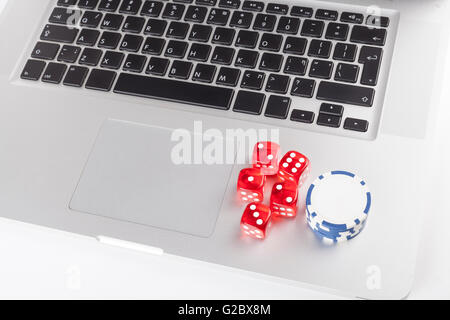 Red casino dices with chips on silver laptop Stock Photo