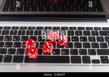 Red casino dices with chips on silver laptop with black Keyboard Stock Photo
