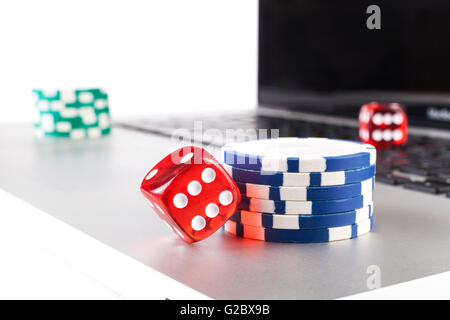 Red casino dices with chips on silver laptop isolated on white background Stock Photo