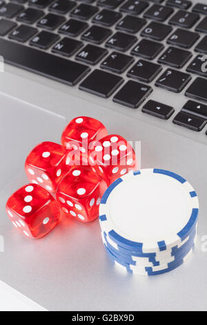 Red casino dices with chips on silver laptop Stock Photo