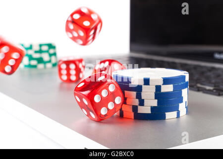 Red casino dices with chips on silver laptop isolated on white background Stock Photo