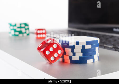 Red casino dices with chips on silver laptop isolated on white background Stock Photo
