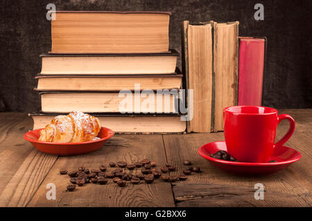 Old Books on Wood Table With Coffee Beans and Croissant Stock Photo