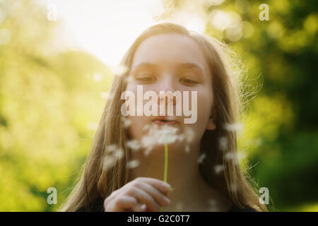 teen girl blowing dandelion to the camera Stock Photo