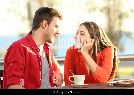 Candid couple date falling in love flirting in a terrace looking each other with tenderness thinking to kiss Stock Photo