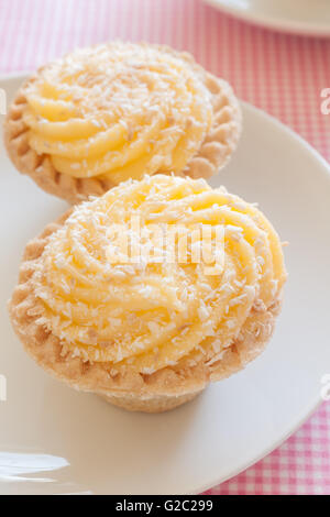 Manchester Tarts pastry cases filled with jam and egg custard dusted with toasted flakes of coconut Stock Photo