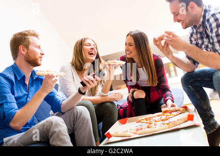 Group of happy young people eating pizza in the room Stock Photo