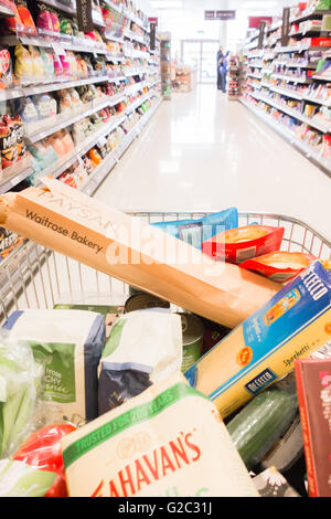 Waitrose shopping trolley full of groceries in shopping aisle Stock Photo