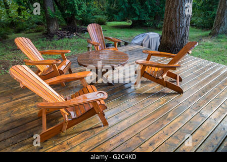 Wooden adirondack chairs on a deck overlooking the water 