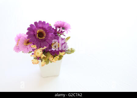 Vintage pink and violet artificial flowers on a white fabric in the bedroom interior concept and design. Stock Photo