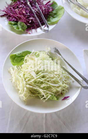 sliced cabbage in a white dish of vegetable salad on food table. Stock Photo