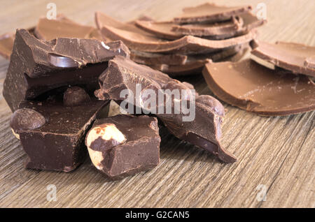 Chocolate with hazelnuts in pieces on a rustic wooden table Stock Photo