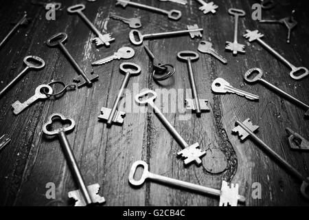 Some door keys on old wooden surface, safety, security concept background. Black and white photo Stock Photo
