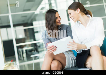 Two pretty young women with tablet in the modern office Stock Photo
