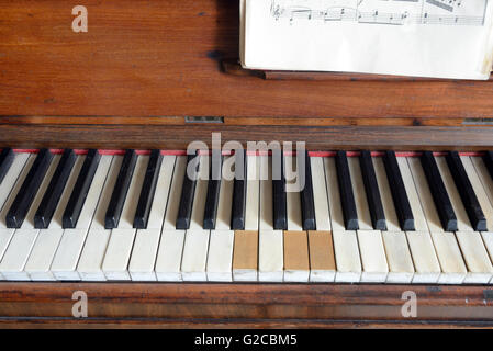 Old Piano with Missing Keys and Sheet Music or Score Stock Photo
