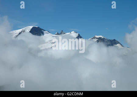 White peaks above clouds nearby Sustenpass in Alps in Switzerland. Stock Photo