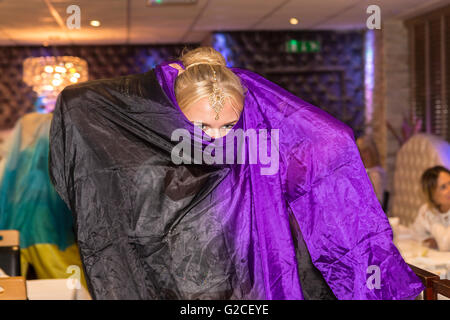 Blond English woman performing a Bollywood dance with a purple and black cloak in an Indian Restaurant in Warrington, England Stock Photo
