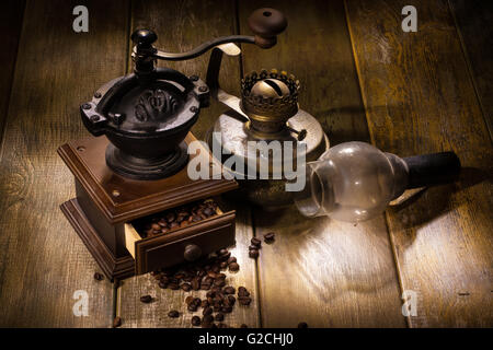 Coffee mill and old oil lamp on a wooden table Stock Photo