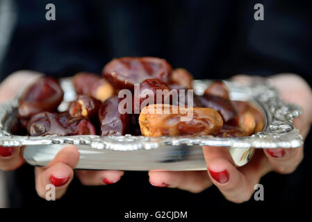Emarati Arab woman holding dates plate, Dubai, United Arab Emirates. Stock Photo