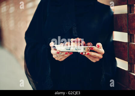 Emarati Arab woman holding dates plate, Dubai, United Arab Emirates. Stock Photo