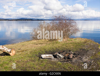 Picnic spot on the Oslo fjord with remnants of a bonfire , springtime in Vollen Asker Norway Stock Photo