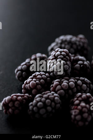 blackberries frozen on a black stone, macro photo showing a beautiful ice texture