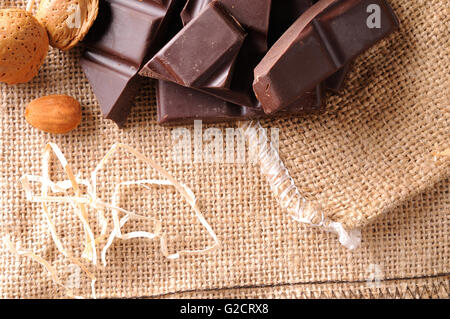 Heap of artisan portions chocolate on burlap sack with almonds with straw decoration. Horizontal composition. Top view. Close up Stock Photo