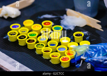 Small pots of coloured tattoo ink on the table in a tattoo parlour Stock Photo