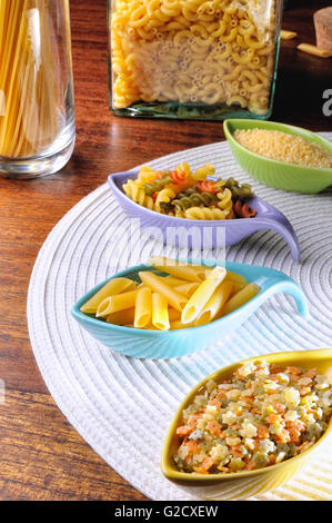 various types of uncooked pasta in ceramic containers on a white tablecloth Stock Photo
